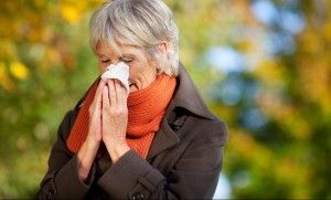 Woman in coat and scarf blows her nose
