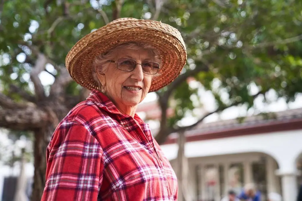 Elderly woman smiling in straw hat outdoors
