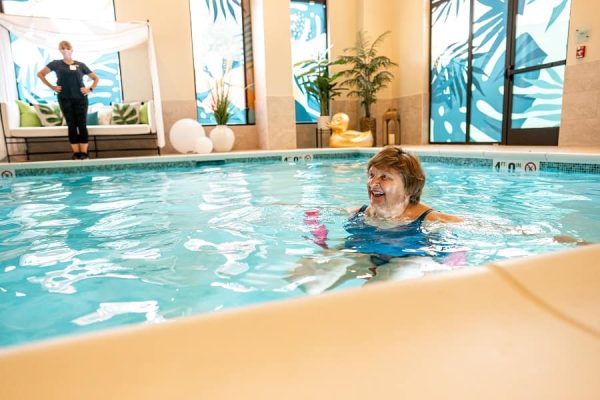 A resident happily floating on a pool noodle in the pool.