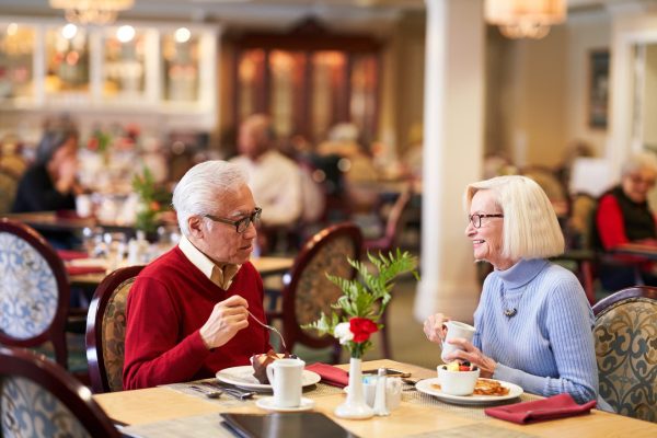 Two residents sitting at a table, eating and talking