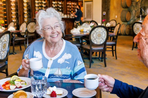 Two residents sitting, smiling, eating breakfast and drinking coffee