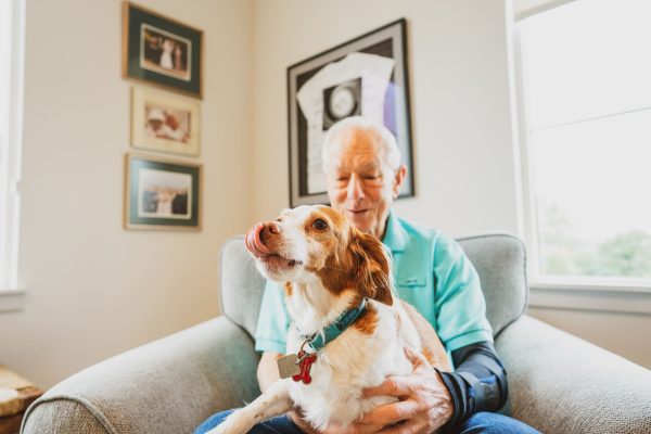 A resident holding a brown and white dog in his lap