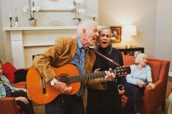 Two residents singing, with the man playing the guitar