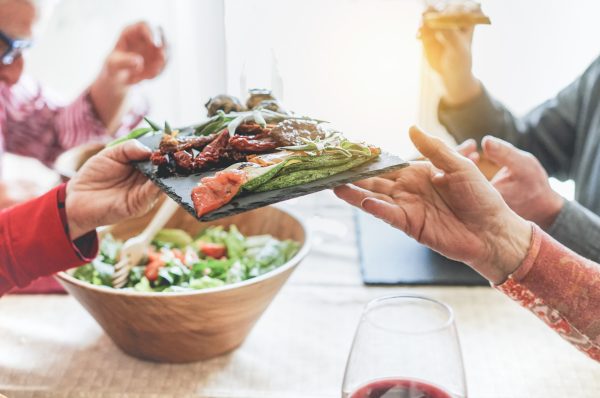 Hands passing a plate of food across a table.