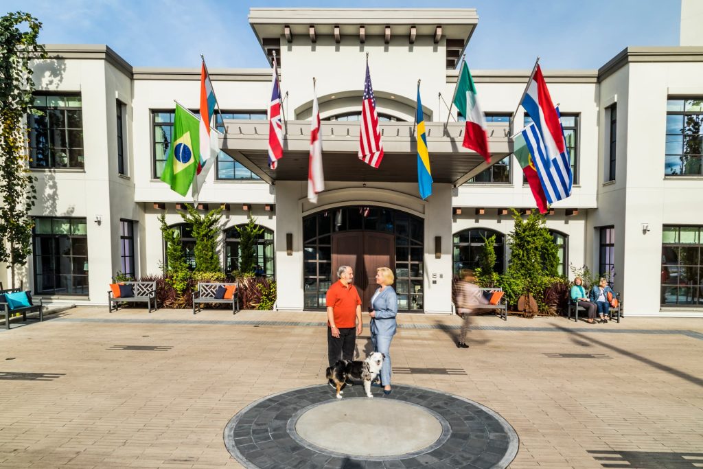 The main entrance of Aegis Living West Seattle, with two women and a dog standing out front