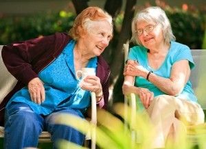 Two elderly women, seated side-by-side and talking