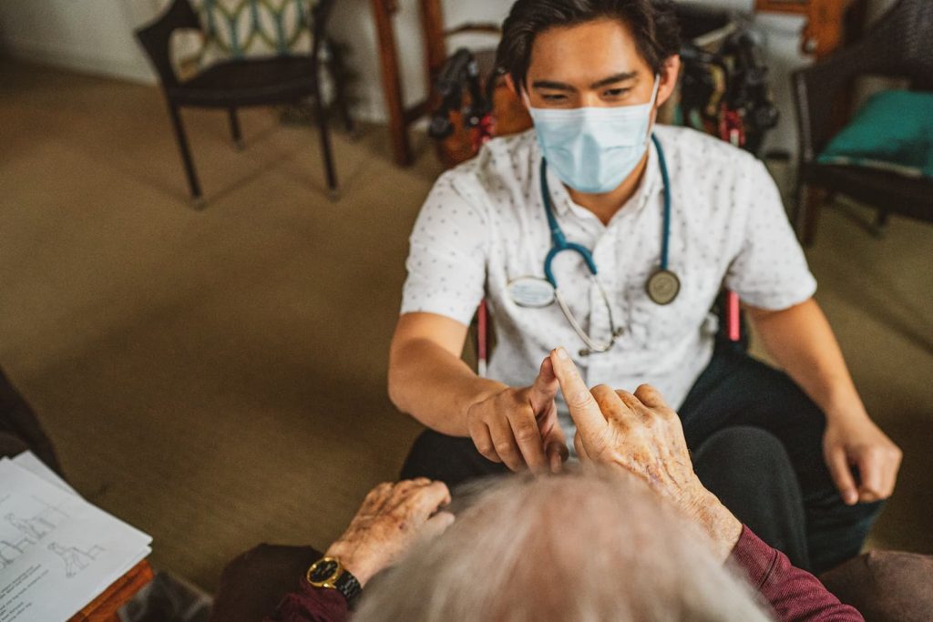 A doctor wearing a mask and a resident touching fingers