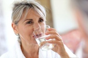 senior woman drinking water from clear glass
