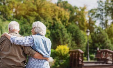 an elder couple hugging outside on a porch