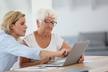 Elderly woman doing her taxes with from her daughter