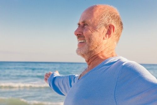 a man stretching his arm with he ocean in the background.