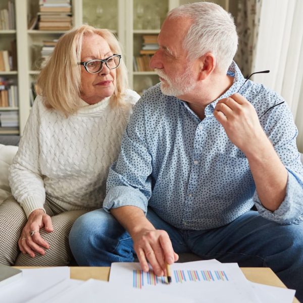 Two people sitting on a couch with paperwork on a table in front of them