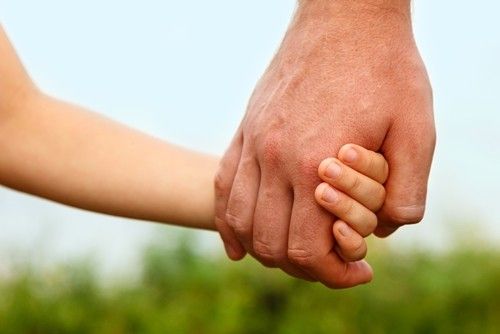 close up of child's and senior man's hands clasped together