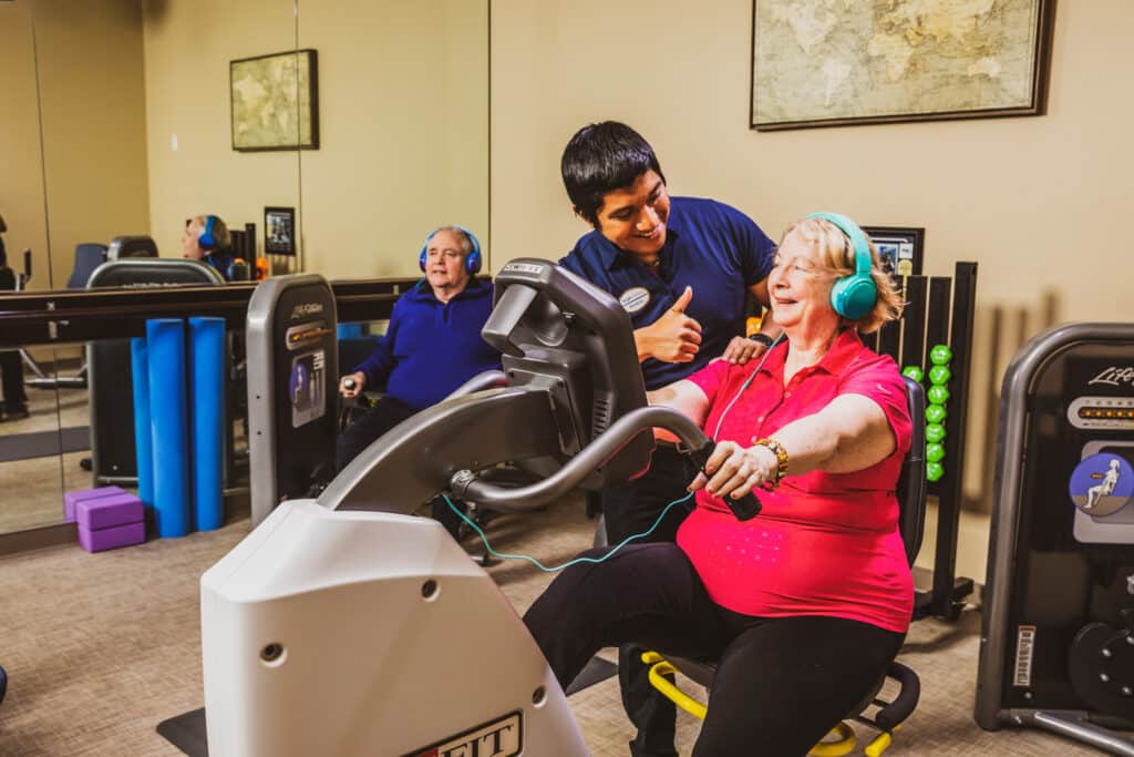 Trainer assists seniors on exercise machines in gym.