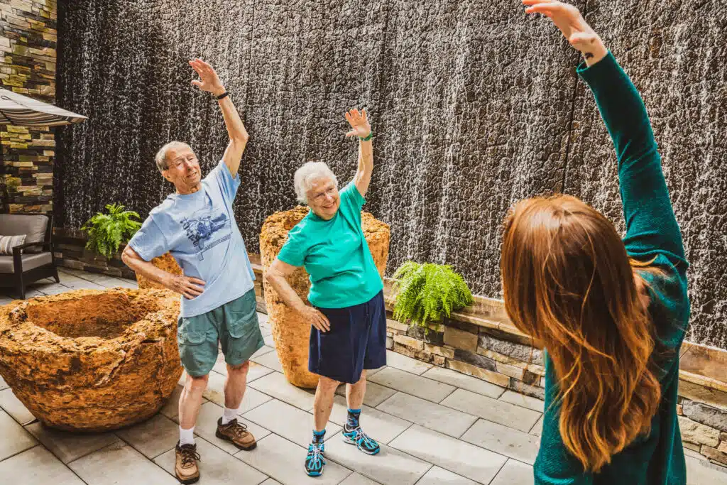 Group stretching exercises outside by a waterfall.