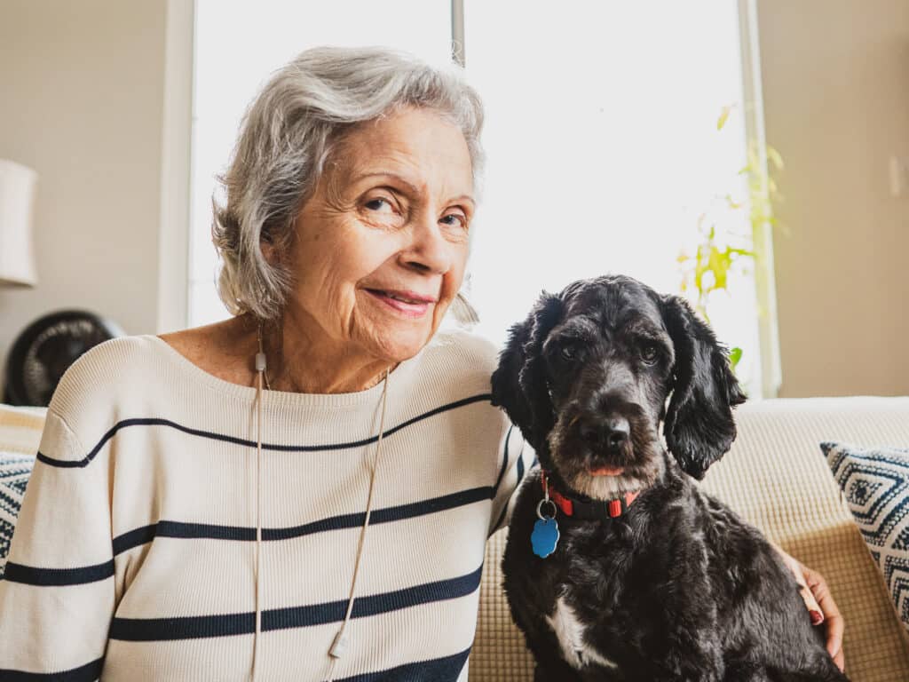 Elderly woman smiling with her dog indoors