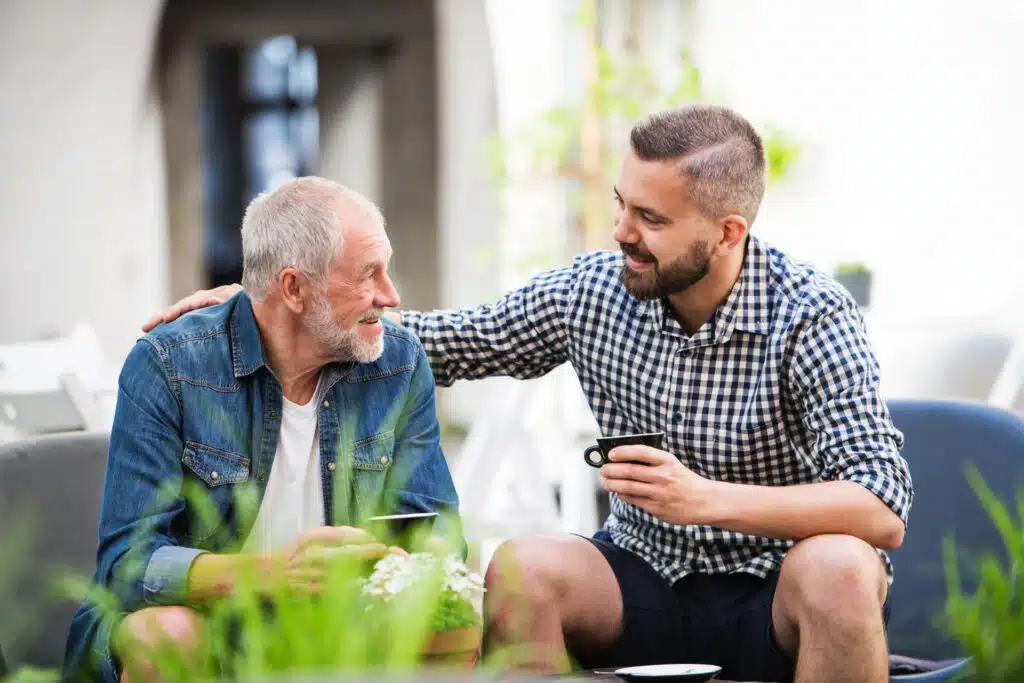 Two men smiling, drinking coffee together.