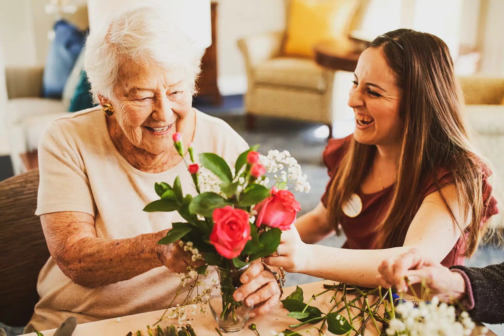 Smiling women arranging flowers together joyfully.