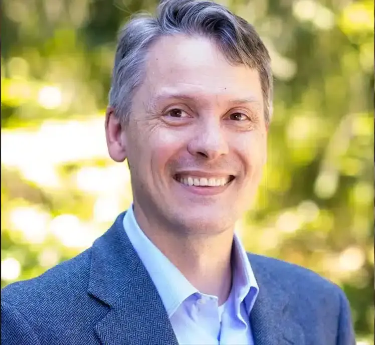 Smiling person in a blue jacket outdoors